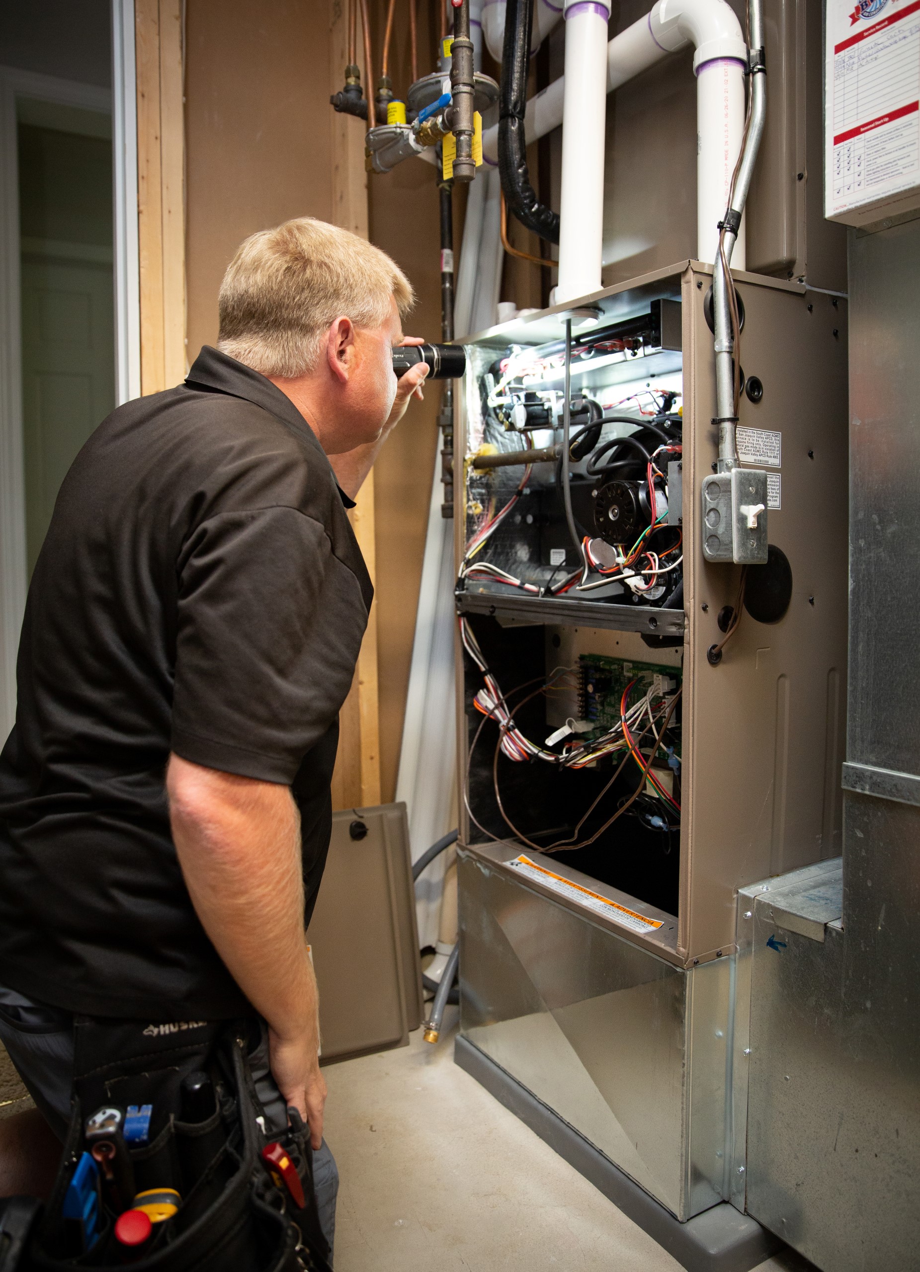 Inspector examining the interior of an air handler cabinet with a flashlight